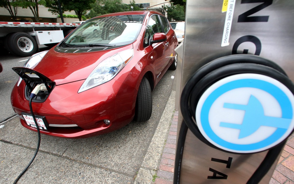 A Nissan Leaf charges at an electric vehicle charging station