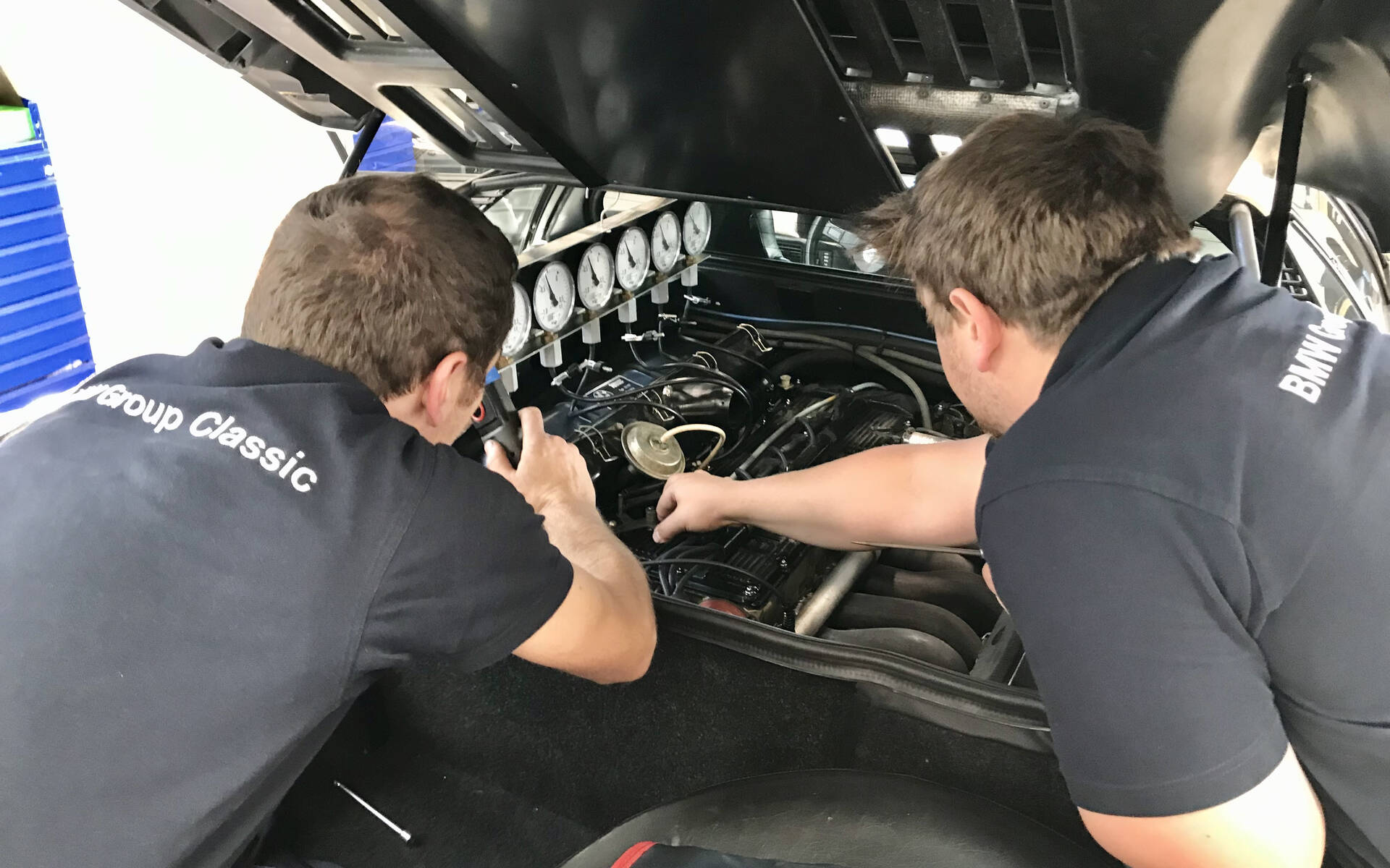 <p>Deux mécaniciens travaillant sur le moteur d'une BMW M1.</p>
