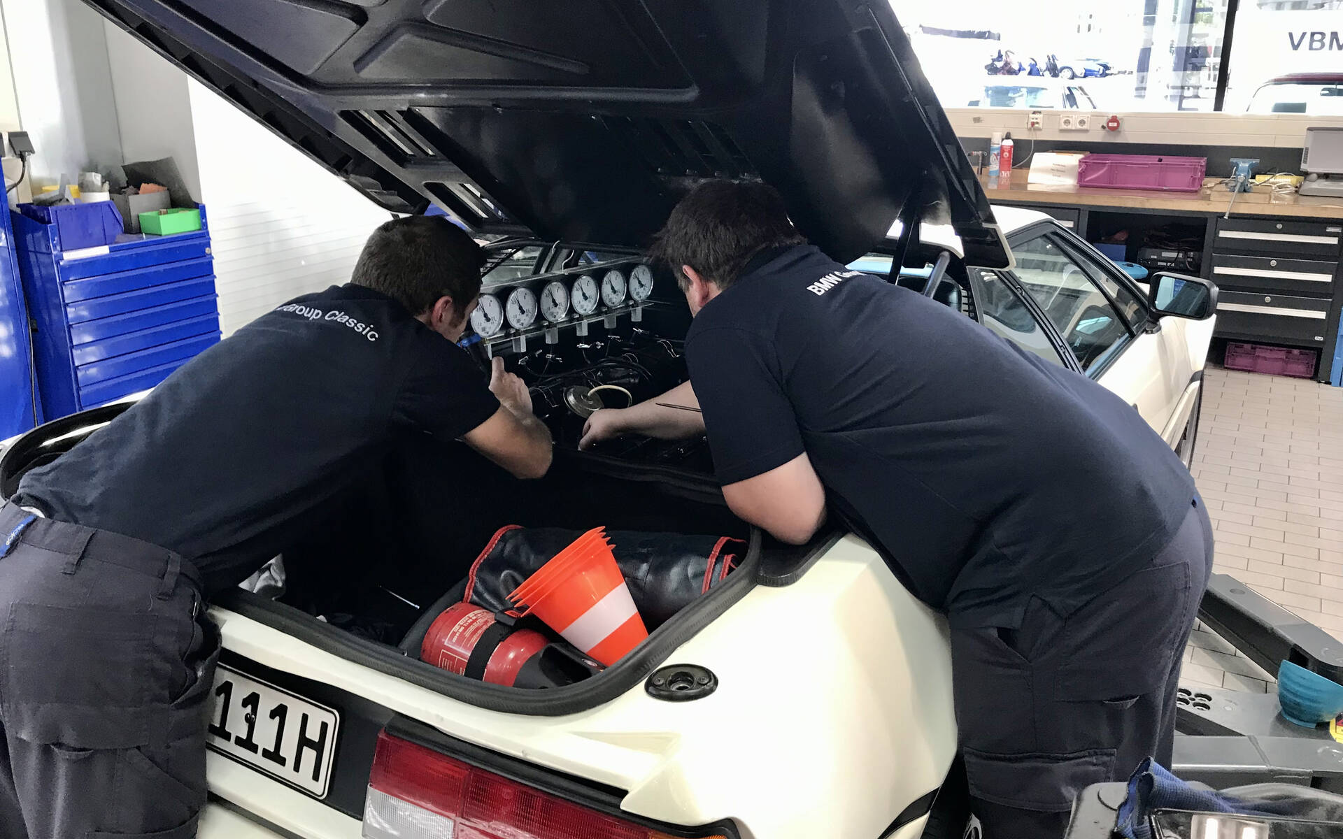 <p>Deux mécaniciens travaillant sur le moteur d'une BMW M1.</p>
